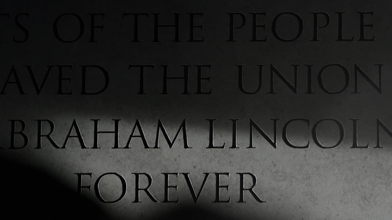 A shadowed black-and-white portrait of Lincoln, heavy with weight